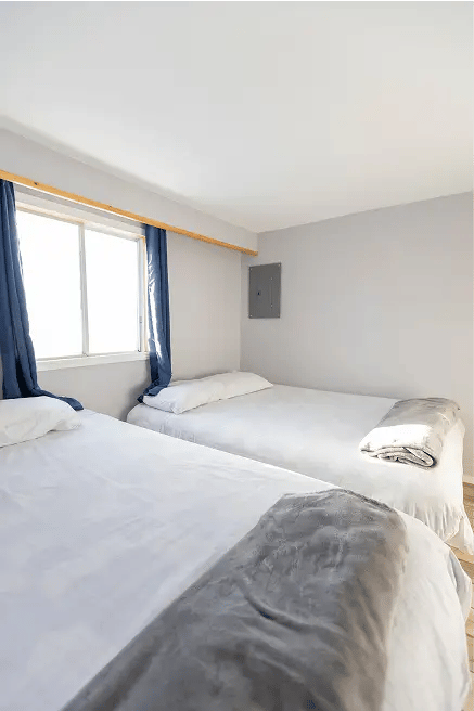 Two beds, white covers, blue curtains