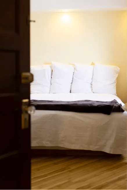 Bed, old character flooring and door. Warm lighting.