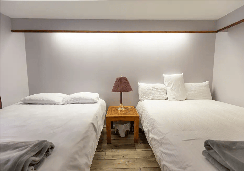 Two beds, white covers, nice lighting.
