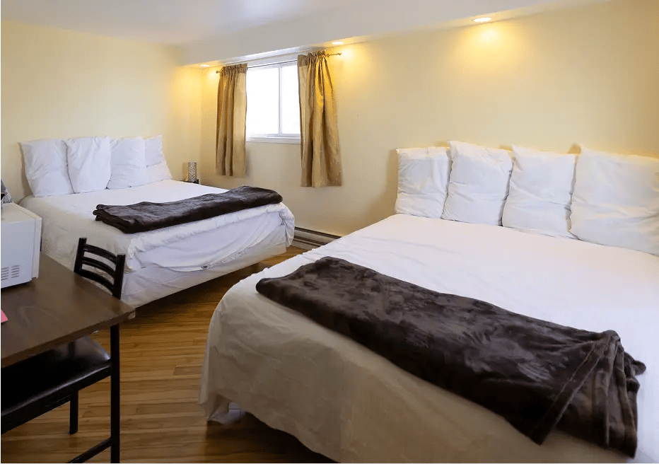 Two beds, white covers, old character flooring. Warm lighting.