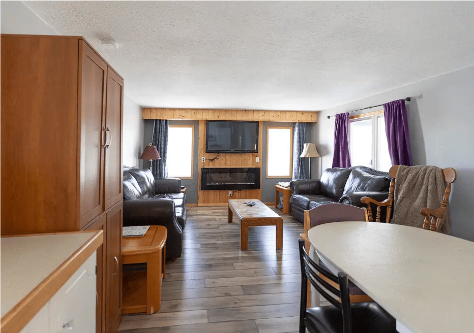Main area with two couches, end table, fireplace, TV, Dining table. 
